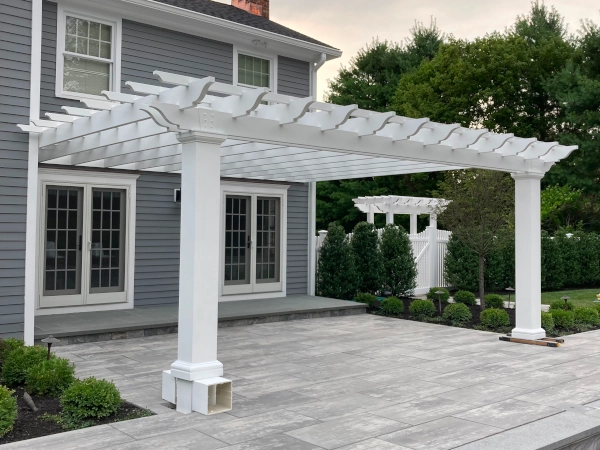 A beautiful white pergola attached to a gray house