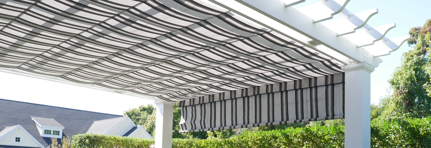 A pergola with a striped fabric roll-up shade